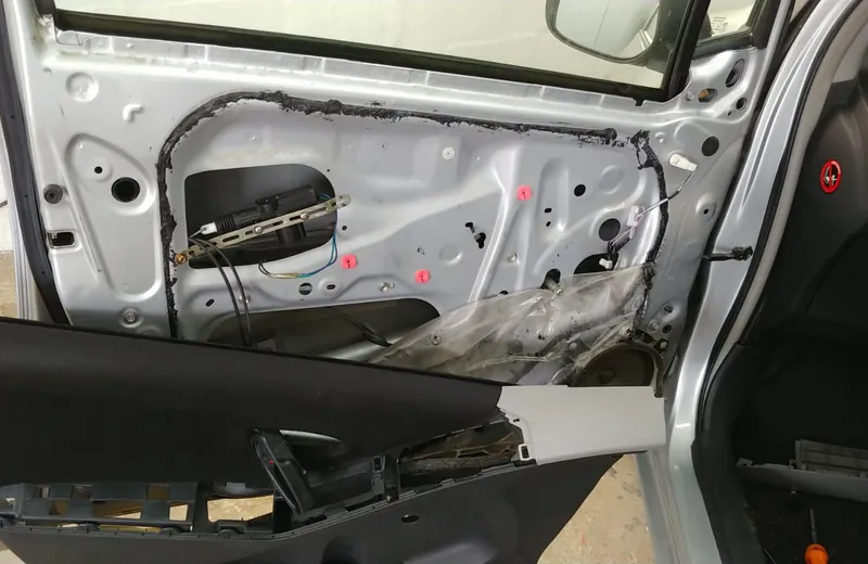 Car door panel removed showing the window regulator, actuator and door wiring at Fangio Auto Hermanus