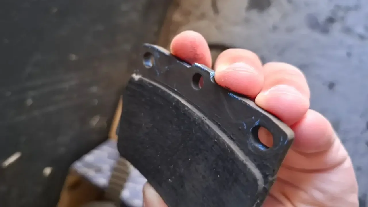 Worn brake pad held in a hand during a Fangio workshop inspection