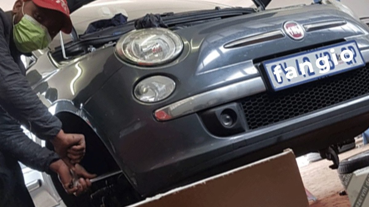 Mechanic working on the front of a Fiat 500 at Fangio