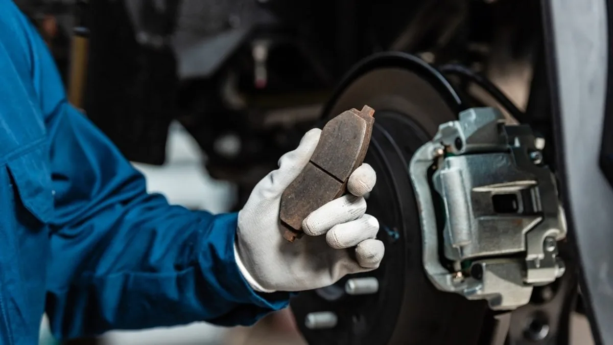 technician inspecting brake pads and discs at Fangio Auto Service
