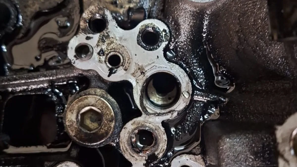 Engine oil leaking down the side of an engine block, the wet gasket face where the leak starts