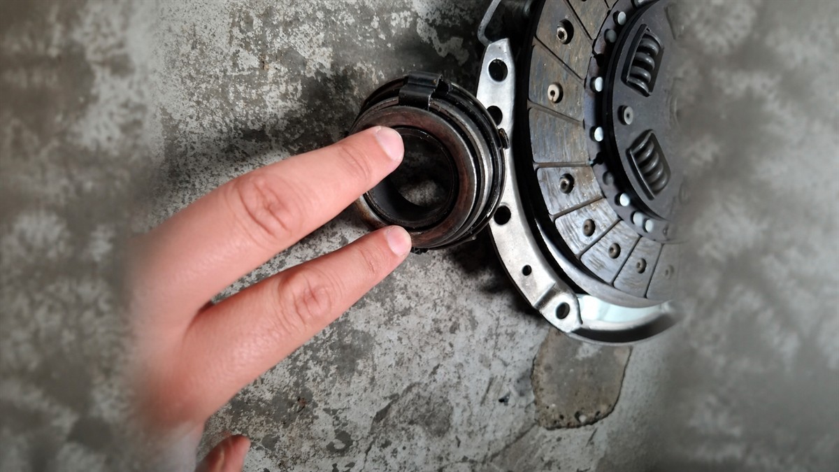 Worn clutch release bearing being pointed out beside clutch parts