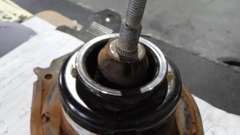 Worn hydraulic engine mounting removed from a car, sitting on a workshop bench