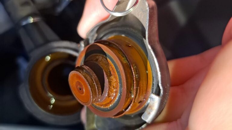 Corroded radiator cap with rusty coolant deposits held in a hand