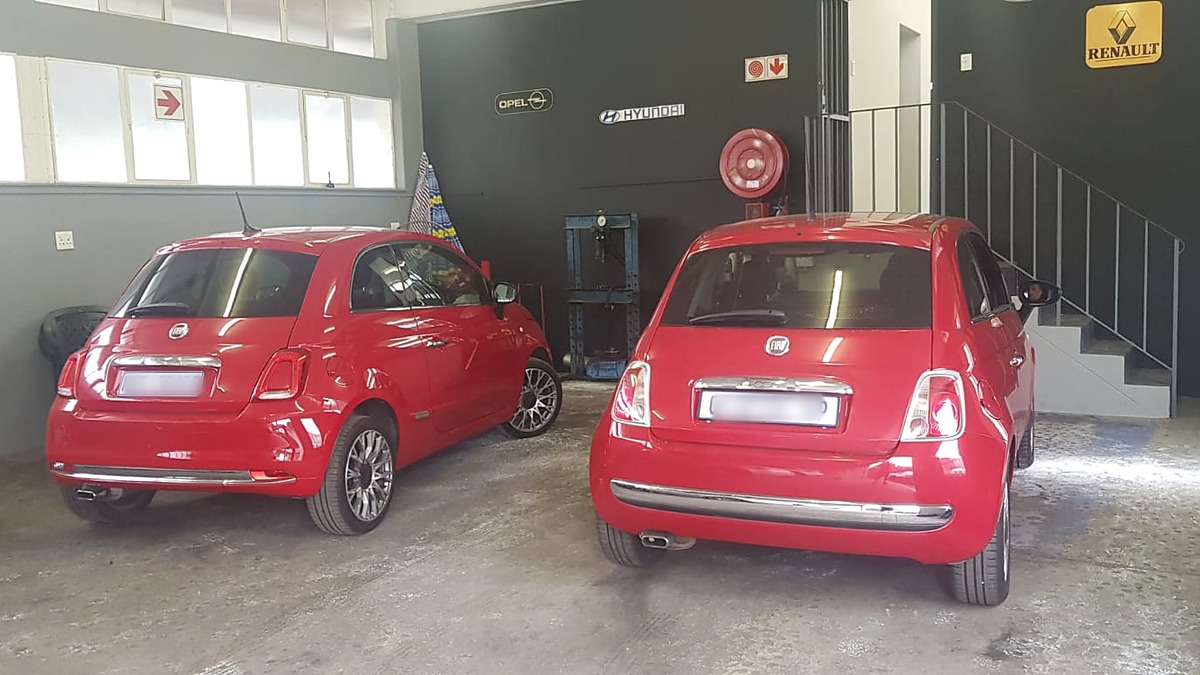Two red Fiat 500s inside the Fangio Auto workshop
