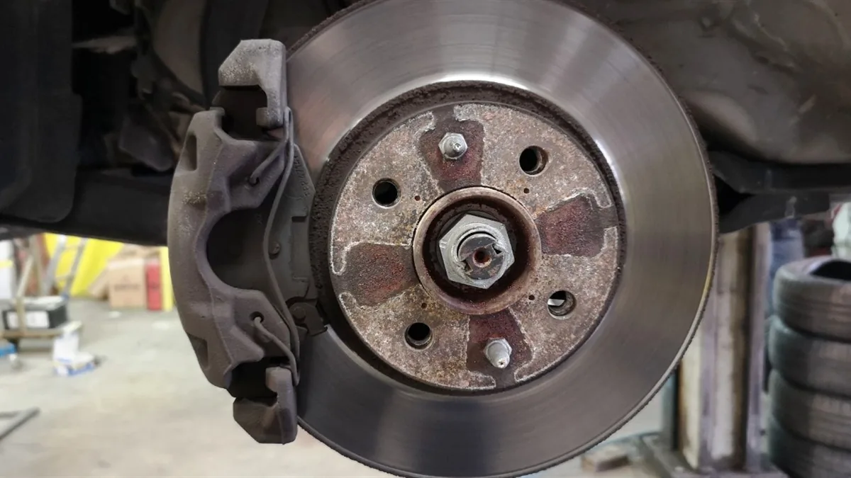 Brake disc and hub runout measured with a dial gauge in a workshop