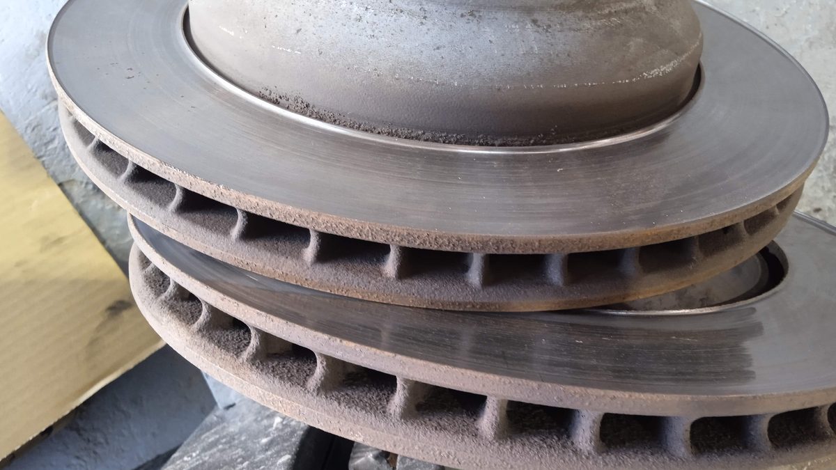Two removed vented brake discs stacked on a workshop bench