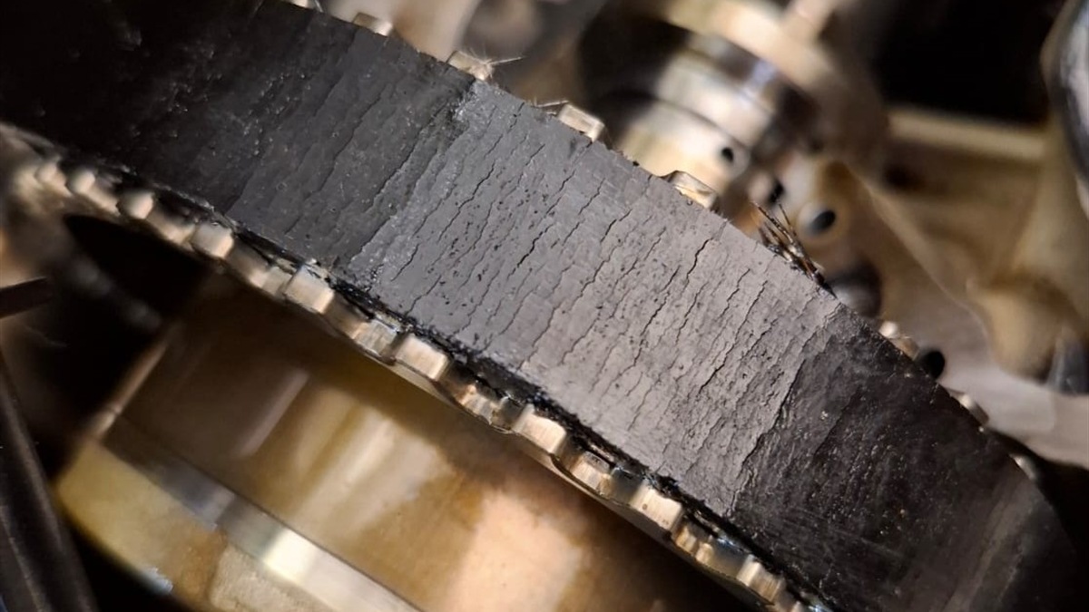 Close-up of a worn timing belt showing cracking and damaged edges